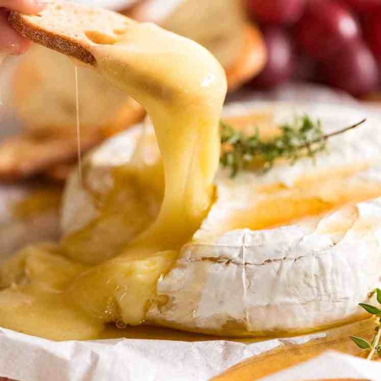 Close up of crispy toasted bread scooping up Baked Brie