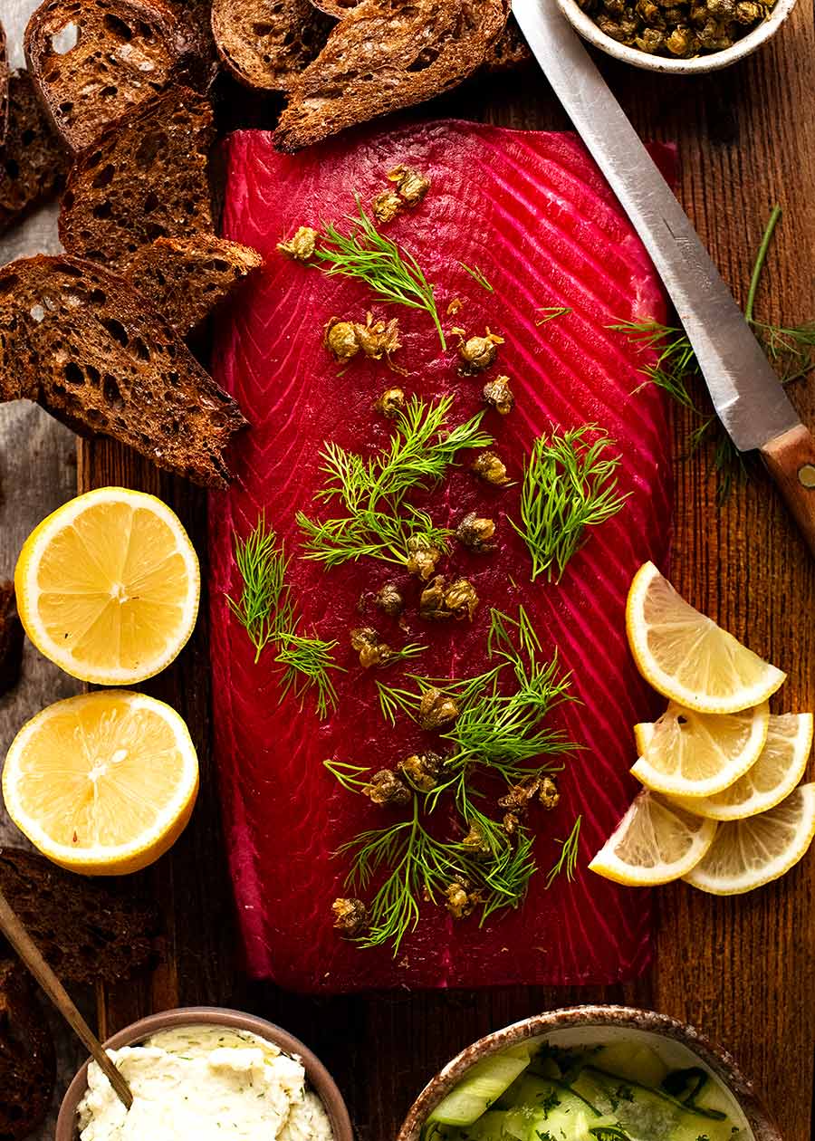 Overhead photo of Beetroot Cured Salmon (Gin or Vodka, Salmon Gravlax) on a wooden board, ready to be served