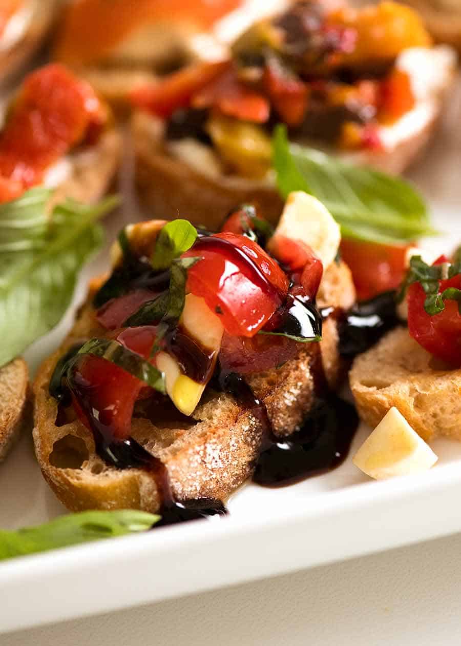 Close up of Caprese Crostini with bocconcini, cherry tomatoes, basil and balsamic glaze