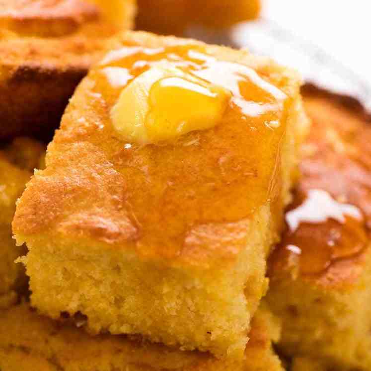 Close up of a piece of Cornbread with butter and honey