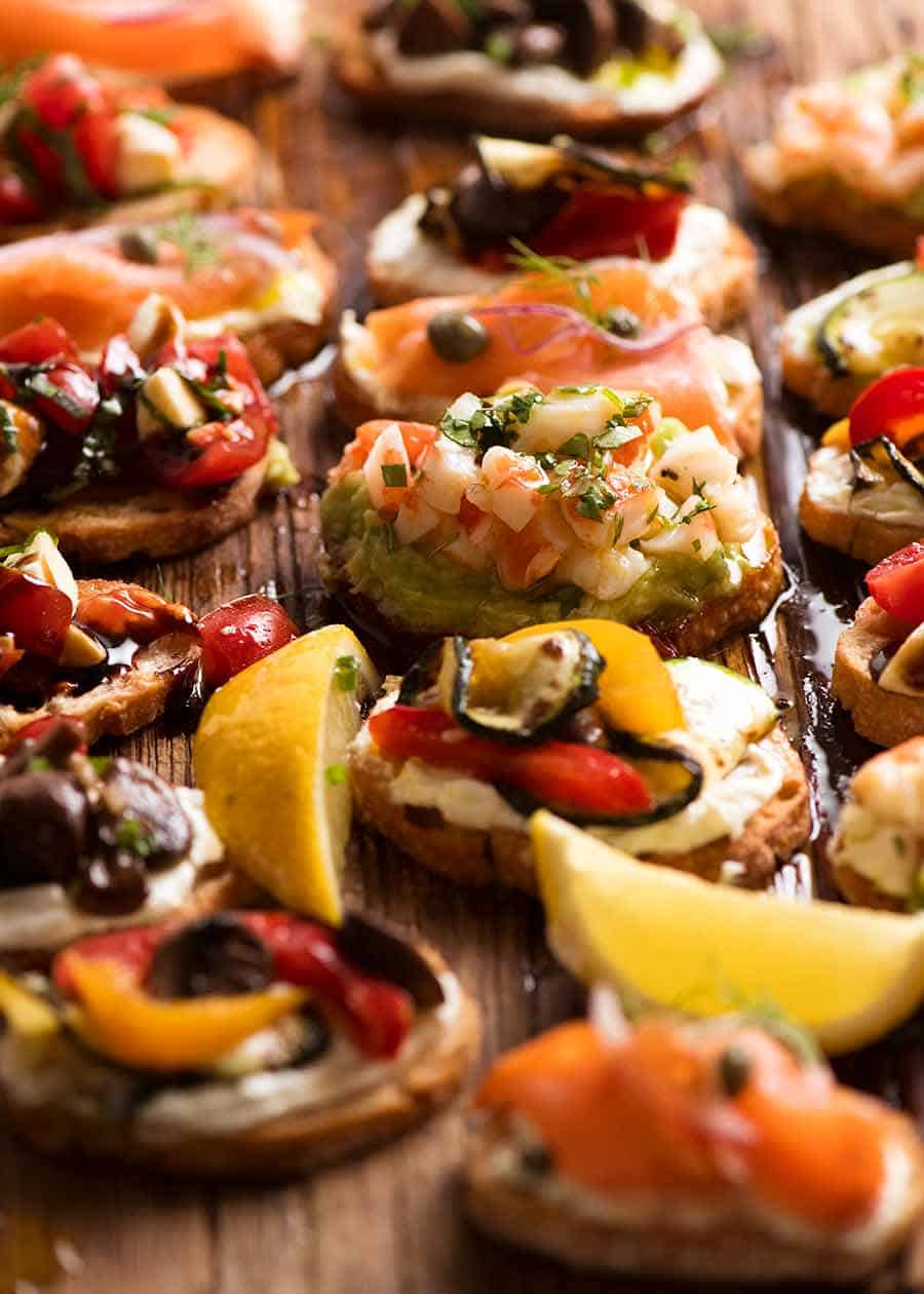 Wooden board filled with Crostini - Smoked Salmon, Shrimp Avocado, Mediterranean and Caprese