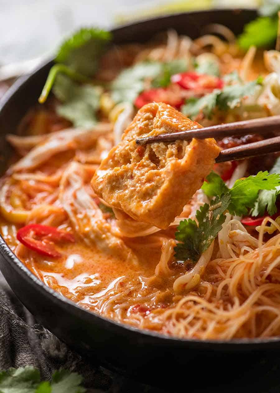 Chopstick holding Fried Tofu Puffs in Laksa