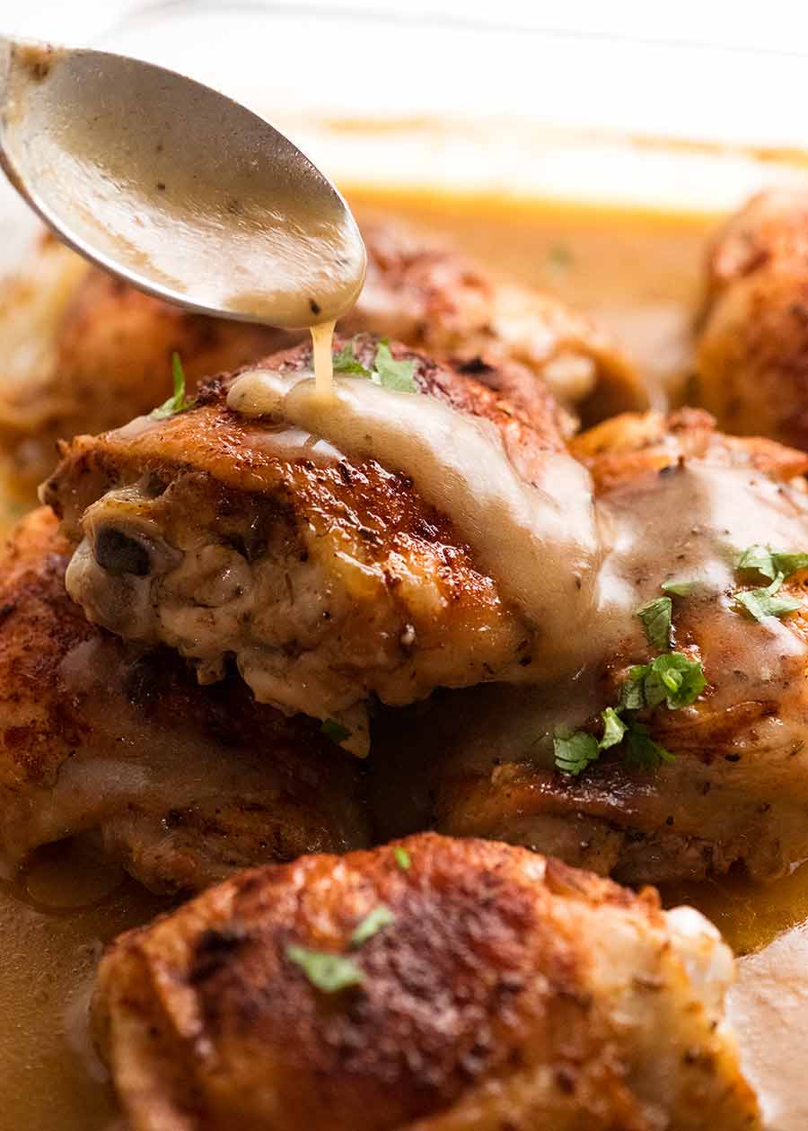 Spoon drizzling gravy over Crispy Baked Chicken in gravy