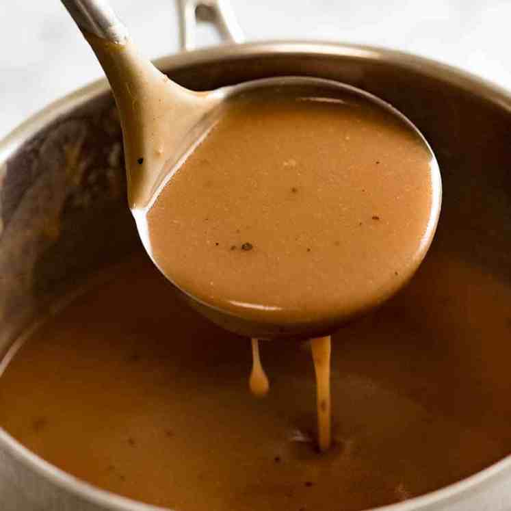 Ladle scooping up gravy from saucepan