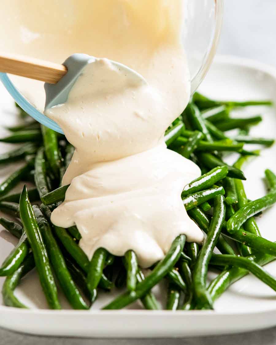 Pouring tahini yogurt sauce over beans