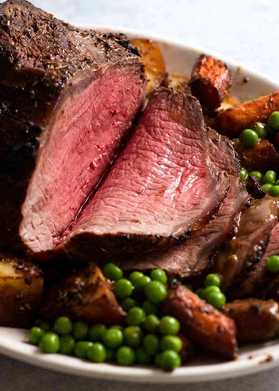 Sliced Marinated Roast Beef on a platter with roasted vegetables, ready to be served