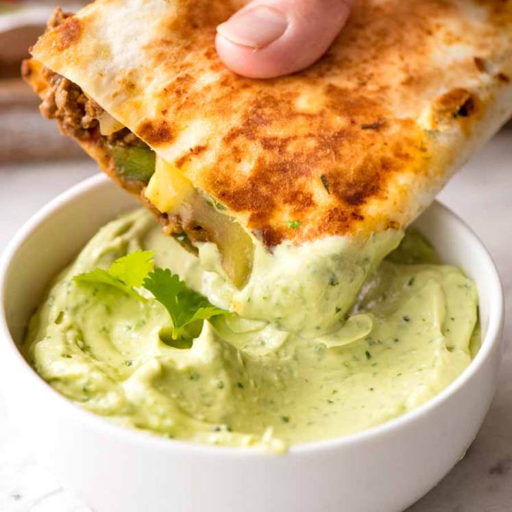 Quesadilla being dipped into Avocado Sauce