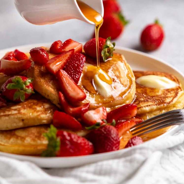 Pouring maple syrup over Ricotta pancakes