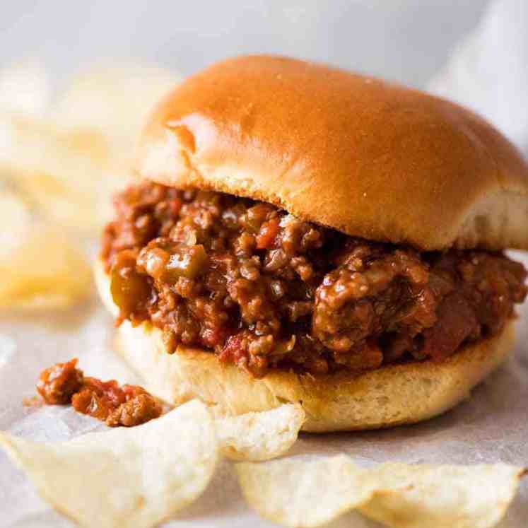 Close up of a Sloppy Joe with potato crisps on the side