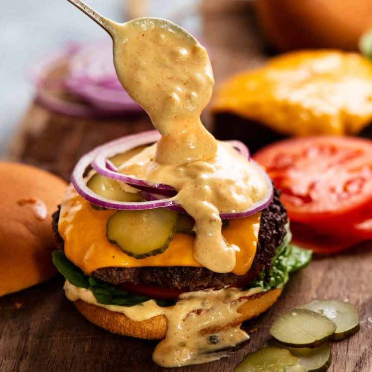 Spooning Special burger sauce onto a cheeseburger