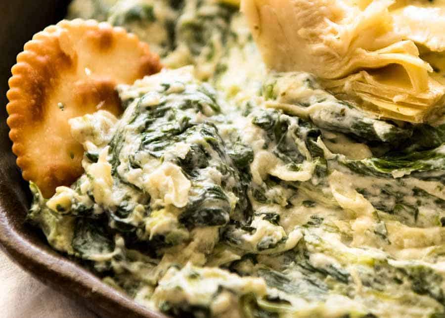 Close up of ritz cracker scooping up Spinach Artichoke Dip