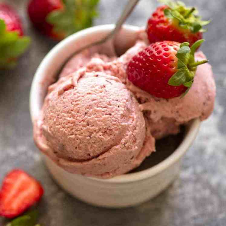 Creamy No Churn Strawberry Ice Cream in a small white dish topped with fresh strawberries, ready to be eaten