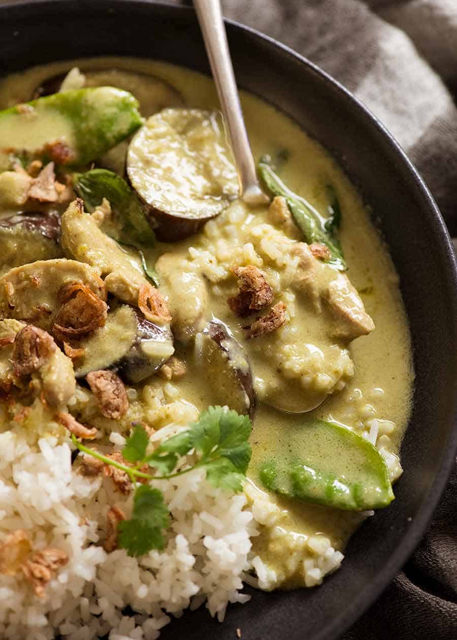 Close up of spoon scooping up Thai Green Curry with chicken served over rice